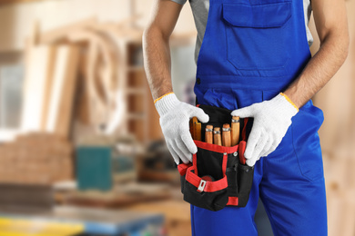 Carpenter with tool belt in workshop, closeup
