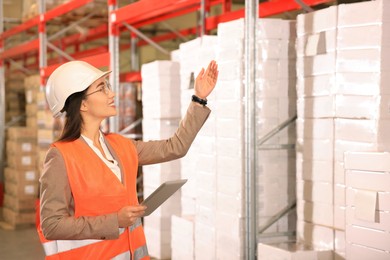Woman with tablet working at warehouse. Logistics center