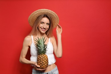 Photo of Young woman with fresh pineapple on red background, space for text. Exotic fruit