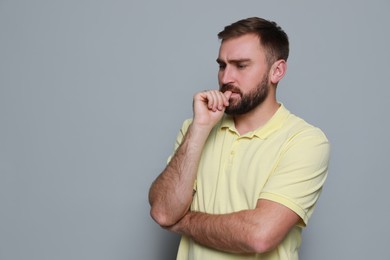 Man biting his nails on grey background, space for text. Bad habit