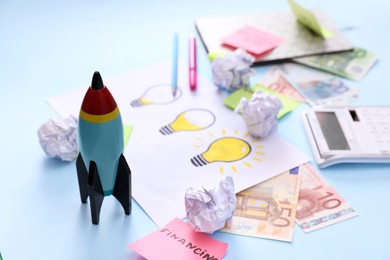 Composition with toy rocket and stationery on light blue background, space for text. Startup concept