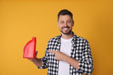 Man pointing at red container of motor oil on orange background