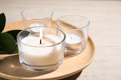Plate with burning small candles on white wooden table, closeup