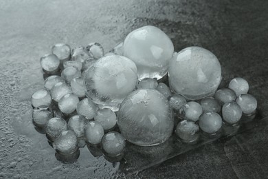 Photo of Many melting ice balls on dark grey table