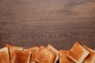 Slices of delicious toasted bread on wooden table, top view. Space for text