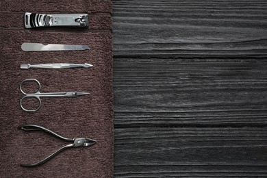 Photo of Set of manicure tools and towel on black wooden table, top view. Space for text