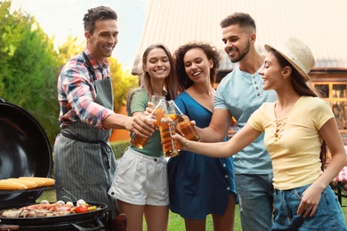 Group of friends with drinks near barbecue grill outdoors