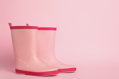Pair of rubber boots on pink background. Space for text
