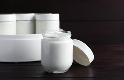 Glass jar with tasty yogurt on wooden table
