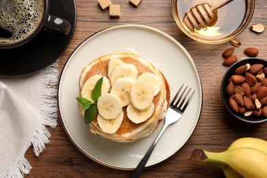Photo of Tasty pancakes with sliced banana served on wooden table, flat lay
