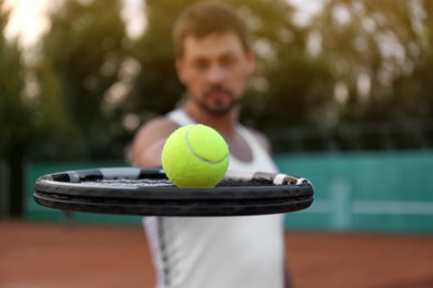 Handsome man playing tennis outdoors, focus on racket