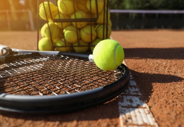 Tennis ball, racket and basket on clay court, closeup