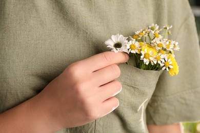 Woman with beautiful tender flowers in shirt's pocket outdoors, closeup