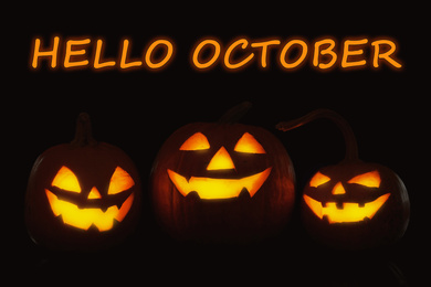 Hello October card. Halloween pumpkin heads glowing in darkness