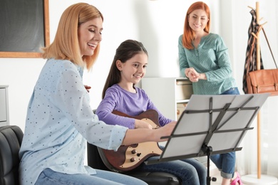 Little girl with her teacher and mother at music lesson. Learning notes