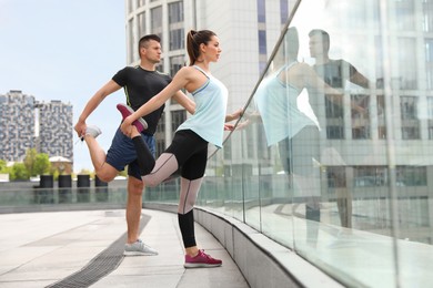 Photo of Man and woman stretching before morning fitness outdoors