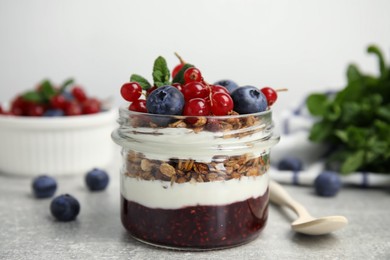 Delicious yogurt parfait with fresh berries and mint on light grey table