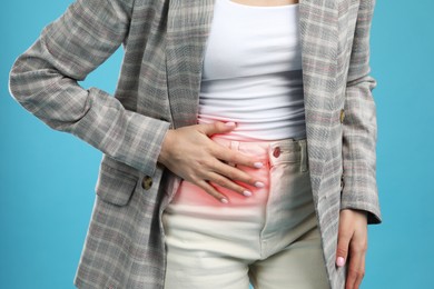 Woman suffering from appendicitis inflammation on light blue background, closeup