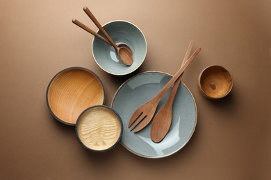 Photo of Stylish empty dishware and wooden cutlery on brown background, flat lay