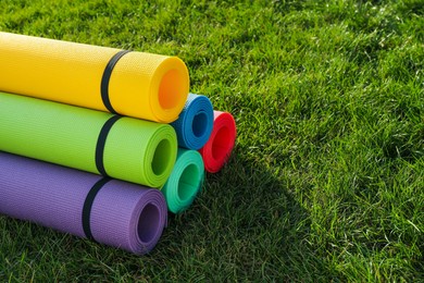 Bright exercise mats on fresh green grass outdoors, space for text