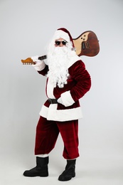Photo of Santa Claus with electric guitar on light grey background. Christmas music