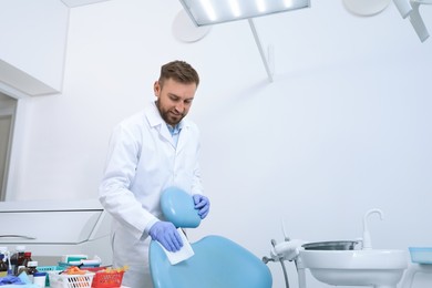 Professional dentist in white coat cleaning workplace  indoors