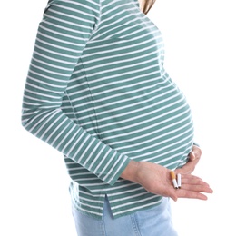Young pregnant woman holding broken cigarette on white background, closeup. Harm to unborn baby