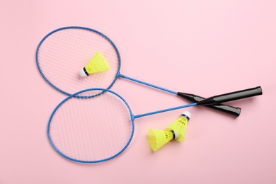 Rackets and shuttlecocks on pink background, flat lay. Badminton equipment