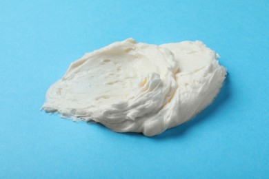 Smear of delicious cream cheese on light blue background