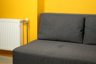 Stylish grey sofa near yellow wall in room