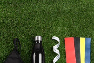 Photo of Flat lay composition with fitness elastic bands on green grass. Space for text