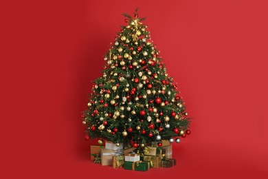 Beautifully decorated Christmas tree and many gift boxes on red background