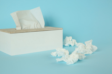 Used paper tissues and holder on light blue background
