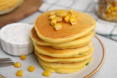 Tasty corn pancakes with sauce served on light grey table, closeup