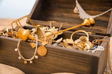 Photo of Open wooden treasure chest on sandy beach, closeup
