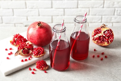 Composition with bottles of fresh pomegranate juice on table