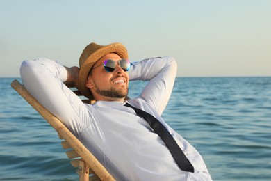 Photo of Happy man resting on deckchair near sea. Business trip