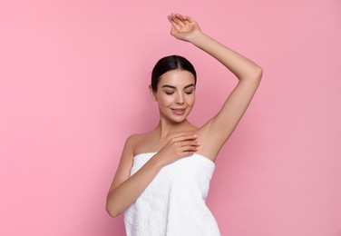 Young woman showing smooth skin after epilation on pink background