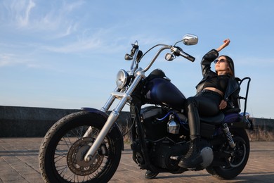 Photo of Beautiful young woman posing on motorcycle outdoors