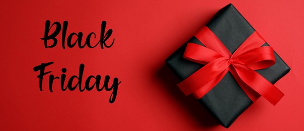 Phrase Black Friday and gift box on red background, top view. Banner design