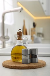 Salt and pepper mills with bottle of oil on table in kitchen