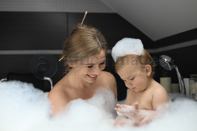 Mother with her child taking bubble bath together indoors