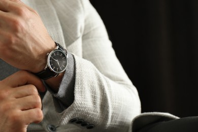 Businessman with luxury wrist watch on black background, closeup