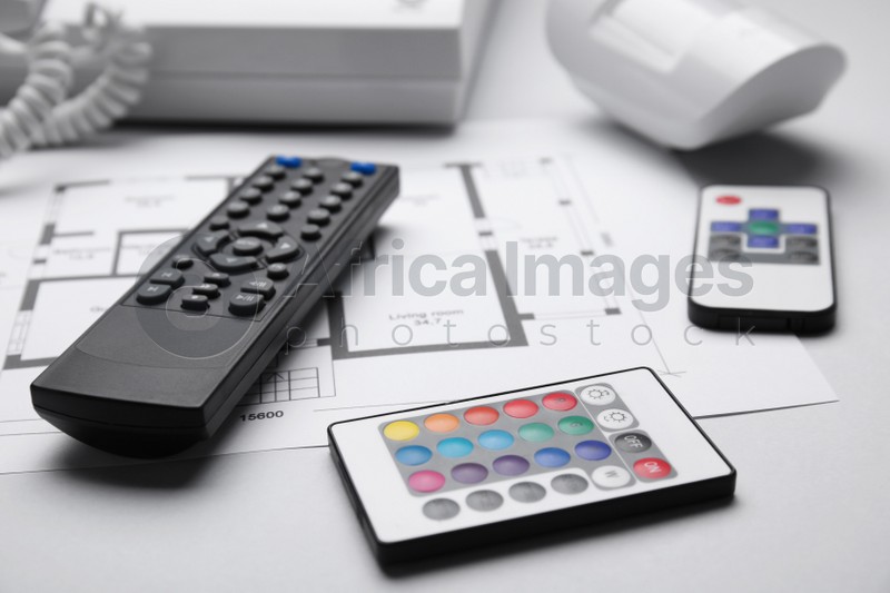 Remote controls and building plan on white background, closeup. Home security system