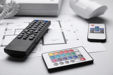 Remote controls and building plan on white background, closeup. Home security system
