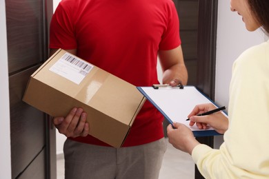 Woman signing for delivered parcel at home, closeup