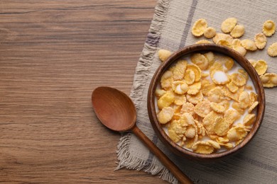 Tasty cornflakes with milk in bowl served on wooden table, flat lay. Space for text