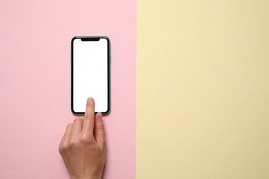 MYKOLAIV, UKRAINE - JULY 07, 2020: Woman using iPhone 11 on color background, top view. Mockup for design
