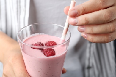 Woman with glass of tasty raspberry smoothie, closeup