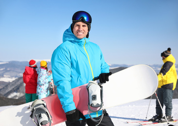 Man with snowboard at ski resort. Winter vacation